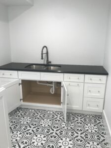 double-bowl laundry sink installed with tile backsplash by licensed plumber